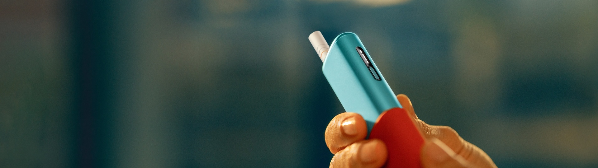 Man holding an IQOS ILUMA i ONE device, seen from left side